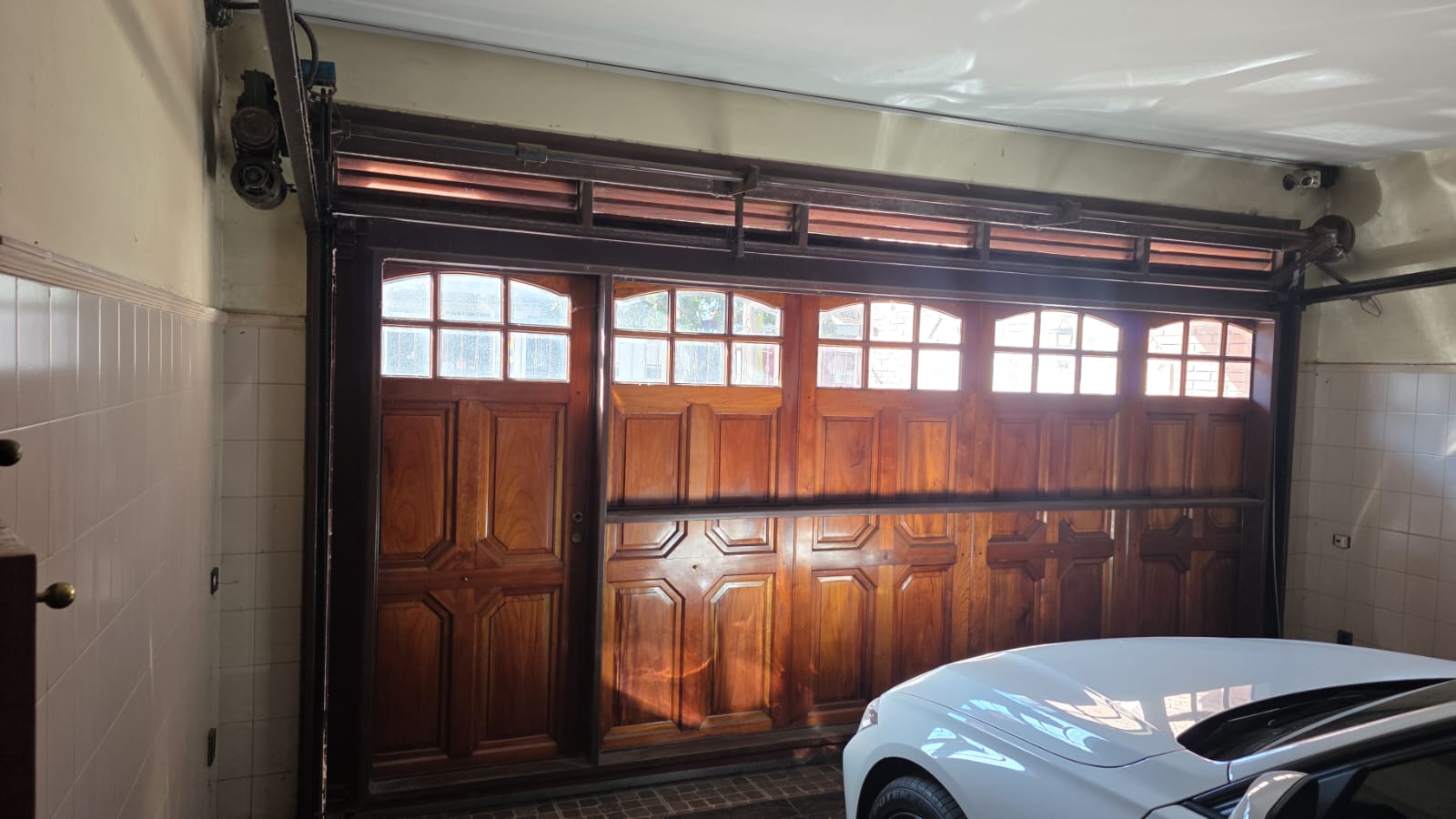 Portón levadizo de madera automatizado en una cochera residencial